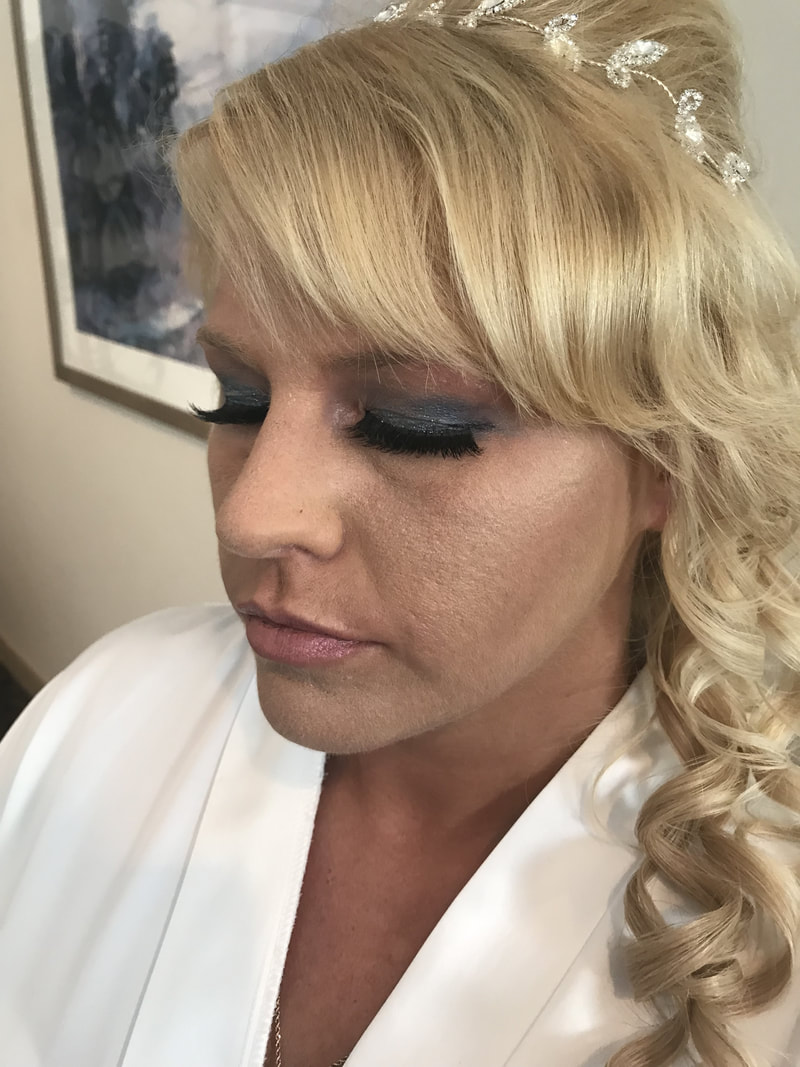 Picture of clients makeup, she has dark blue eye shadow and her hair is blonde that is curled